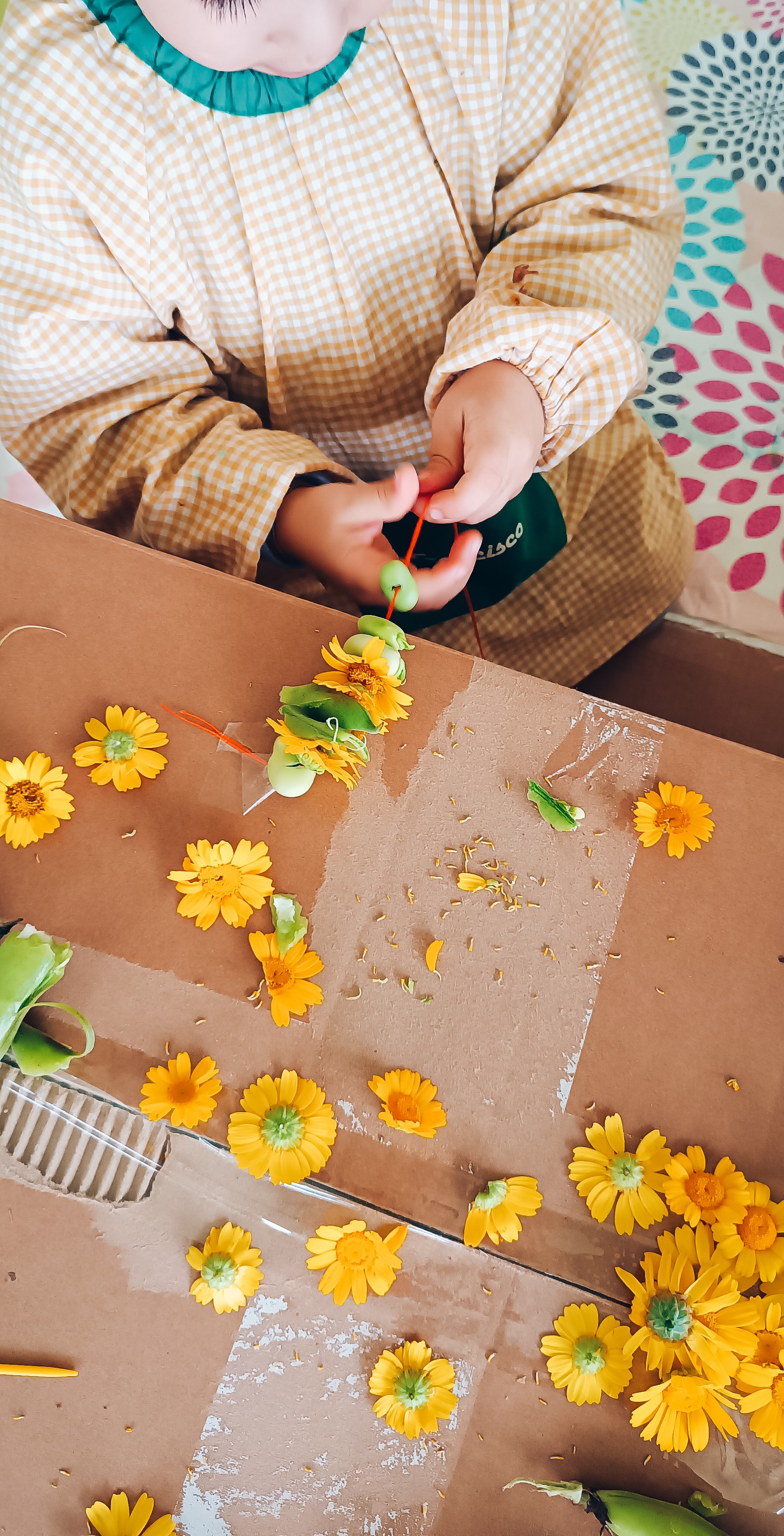 Criança a criar colares de flores amarelas